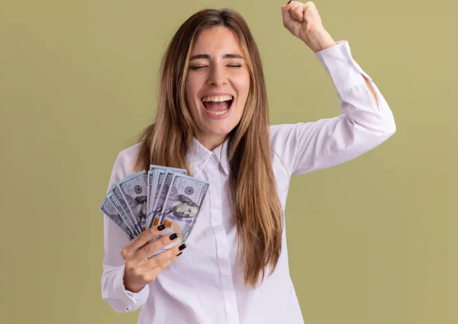 joyful-young-pretty-caucasian-girl-holds-money-keeps-fist-up-isolated-olive-green-wall-with-copy-space_resultado